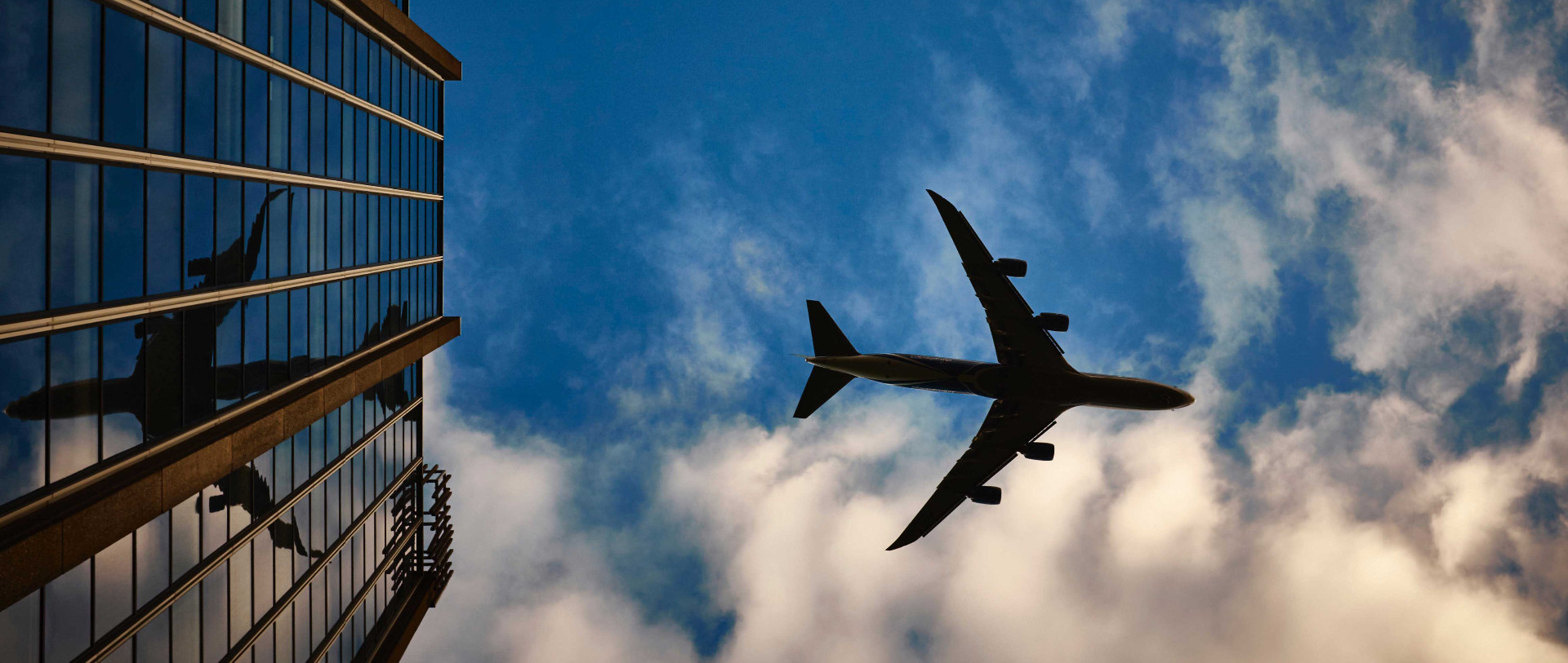 Jet passanger plan against a blue sky flying over an office block